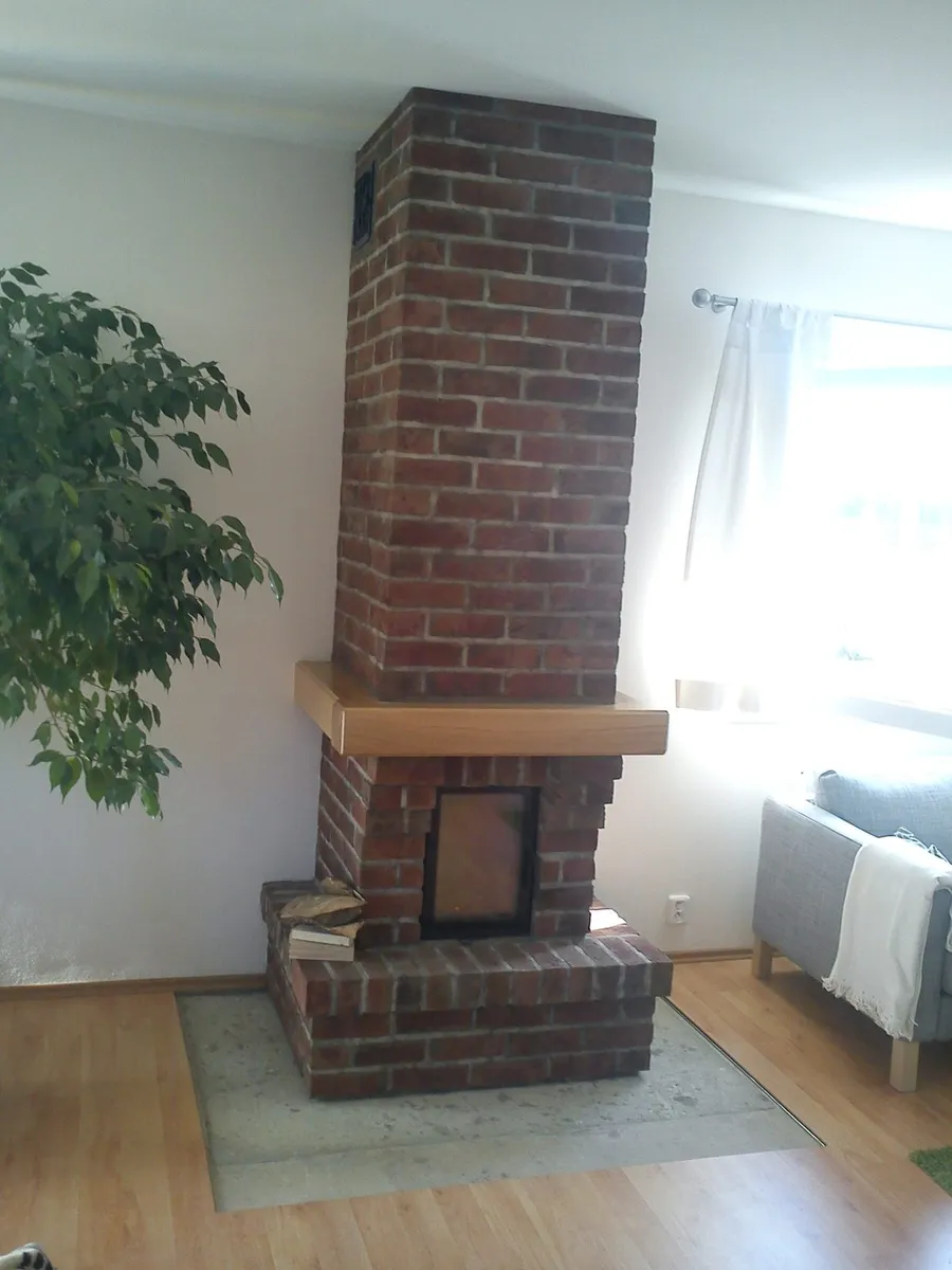 Cihlový krb s&nbsp;dřevěnou římsou a&nbsp;viditelným cihlovým komínovým tělesem až ke stropu