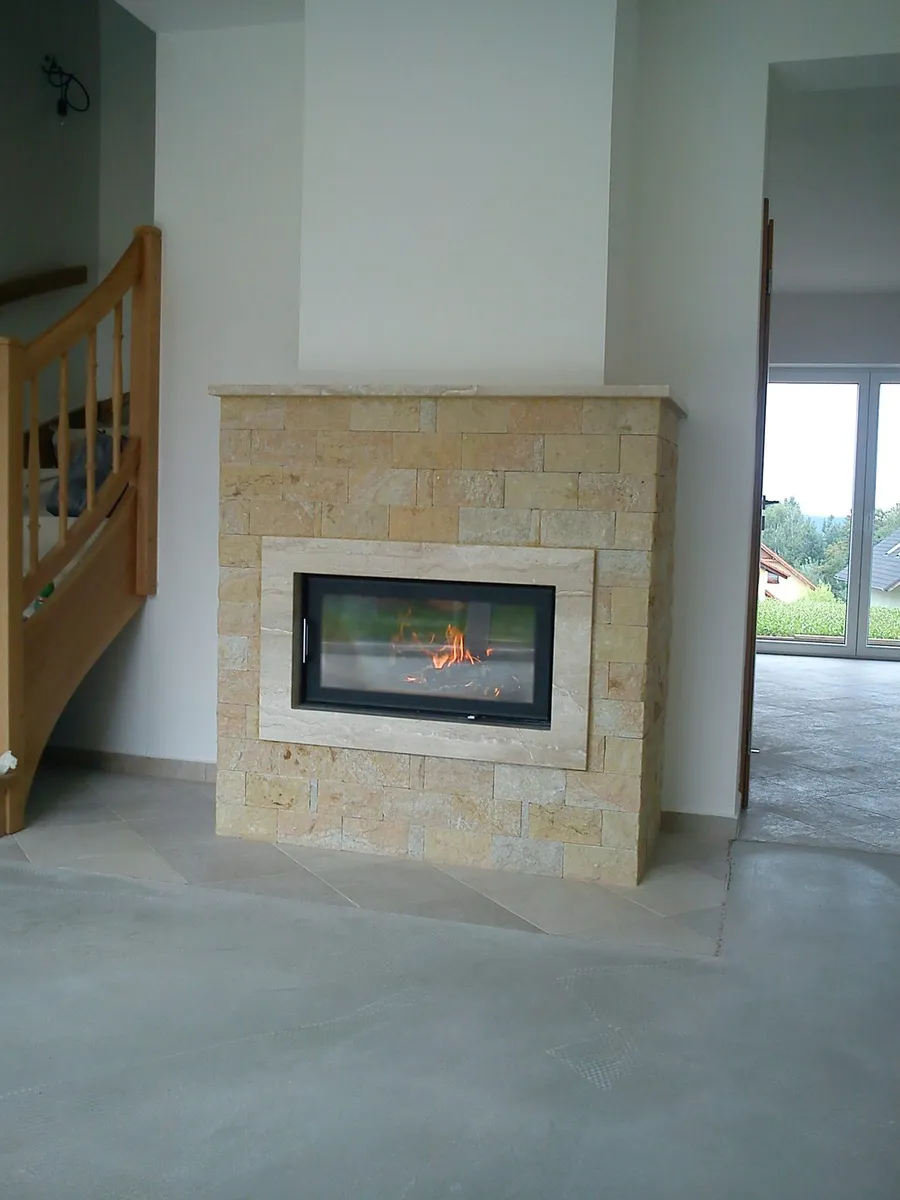Krb obložený světlým pískovcem s&nbsp;velkou prosklenou vložkou a&nbsp;hořícím ohněm